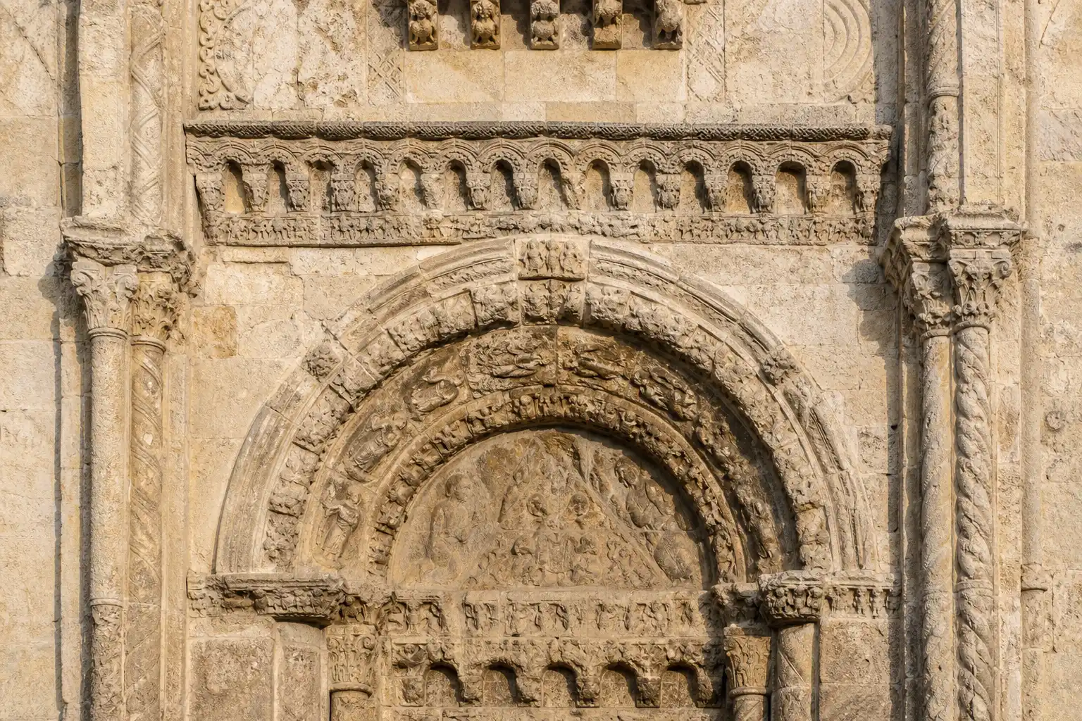 A carved stone archway on a cathedral facade, lit from the side